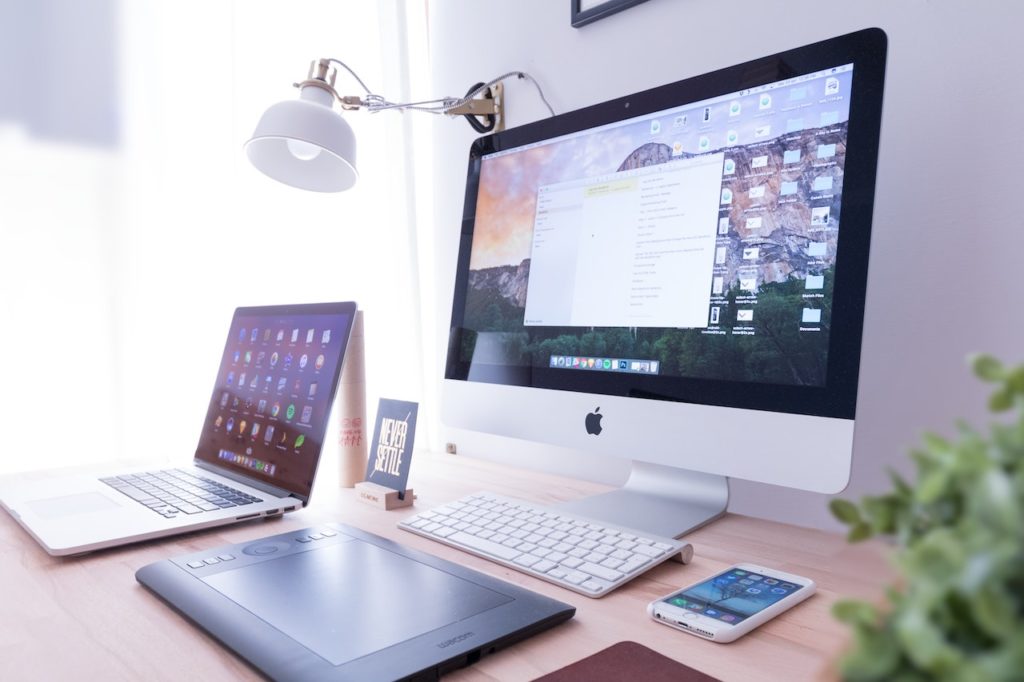 mac desktop and laptop screens on desk